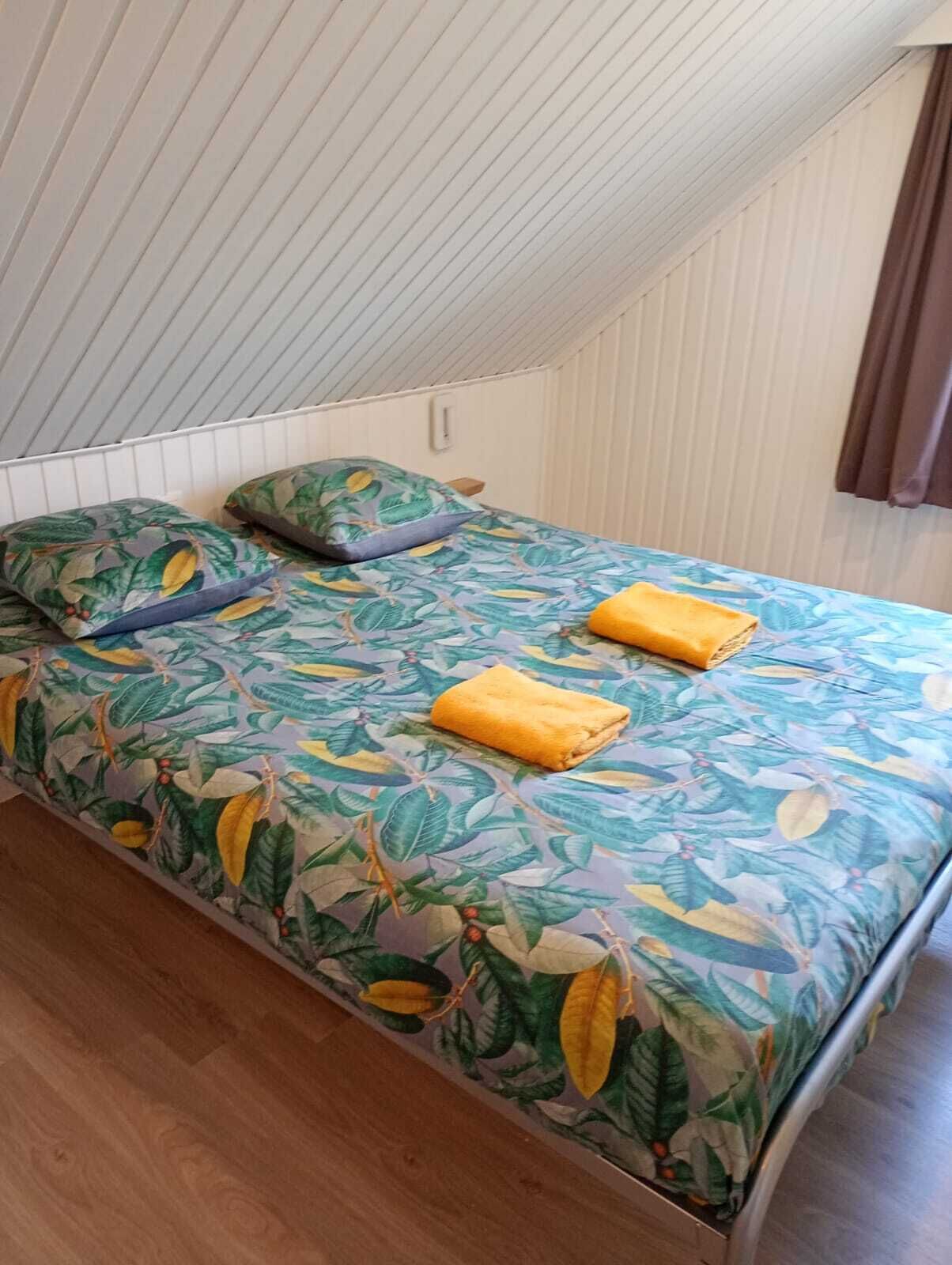 A small, single-bed room with a sloped ceiling and wooden flooring.