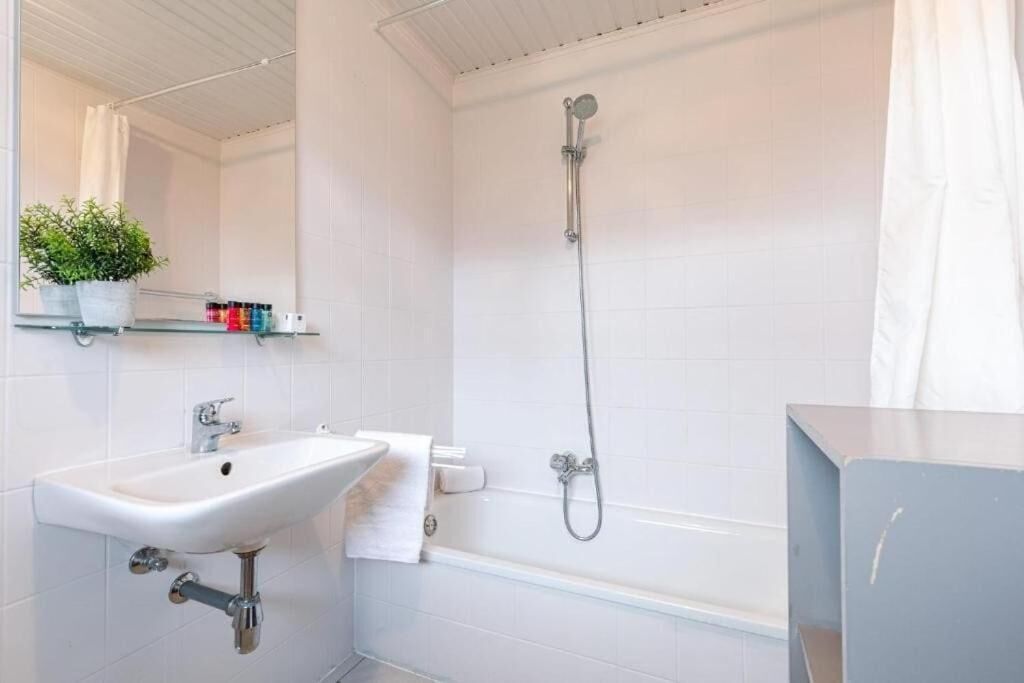 Ein modernes Badezimmer mit einem weißen Waschbecken, einer Badewanne und einer Dusche.