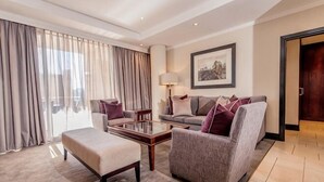 A modern living room with a sofa, armchair, ottoman, and coffee table. - Raphael Suites (Sandton)