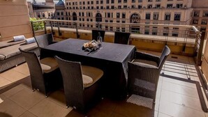 A rooftop terrace with a table and chairs, a view of a historic building, and a railing. - Raphael Suites (Sandton)