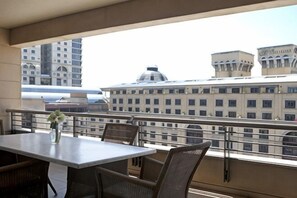 A balcony with a table and chairs, overlooking a cityscape with buildings. - Raphael Suites (Sandton)