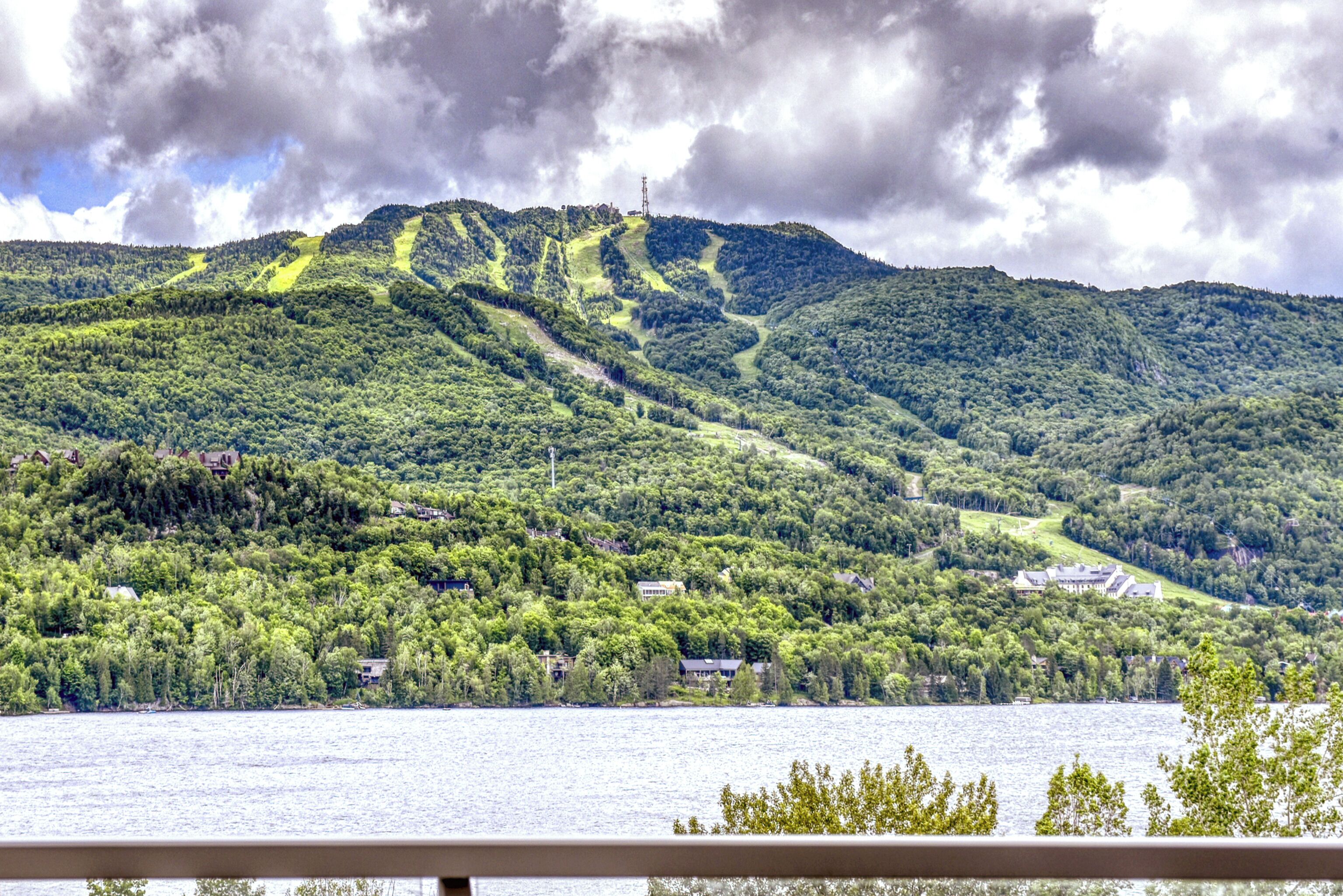 A mountainous landscape with a lake, houses, and a ski lift.