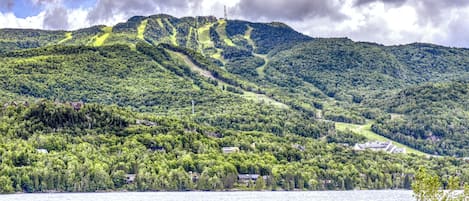 A mountainous landscape with a lake, houses, and a ski lift.