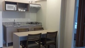 A compact kitchen with a microwave, stove, and sink. There is a dining table with four chairs. - SaltBeach - Salinas Park Resort (Salinópolis)