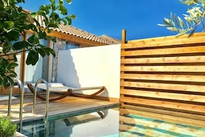 Une piscine avec une terrasse en bois, une chaise longue et une clôture en bois.