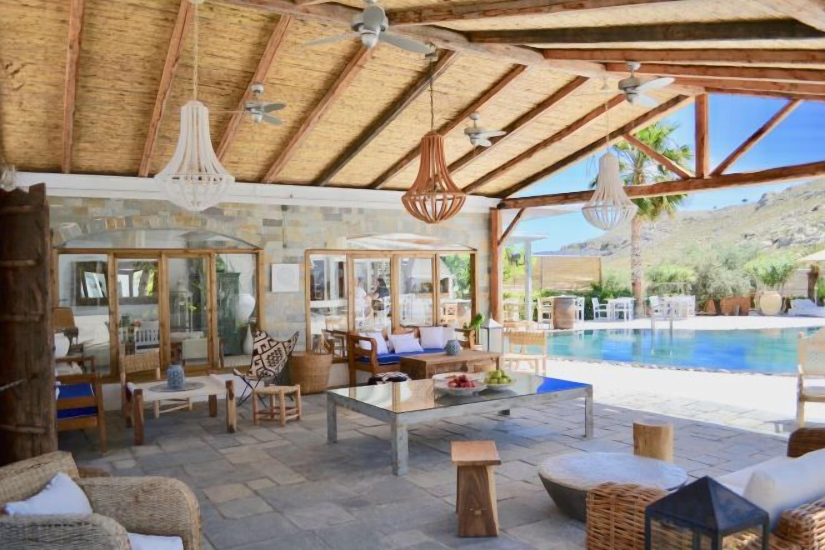 A covered outdoor area with a pool, seating, and a stone wall.