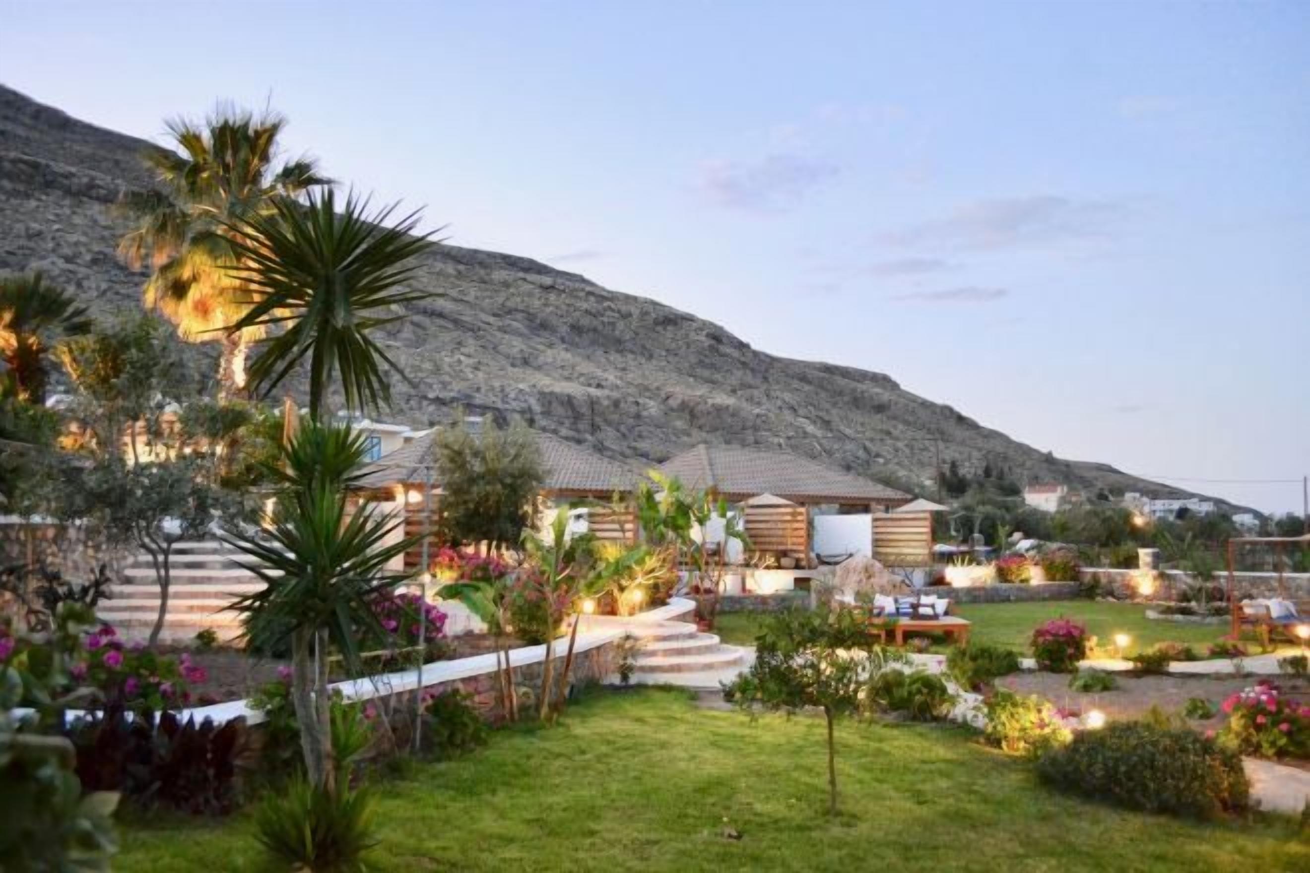 A hotel with multiple buildings, a well-maintained garden, and a mountain in the background.