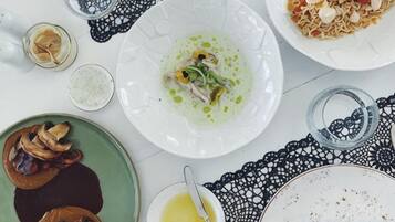 Una mesa de comedor con diversos platos, un mantel de encaje y un vaso de agua.