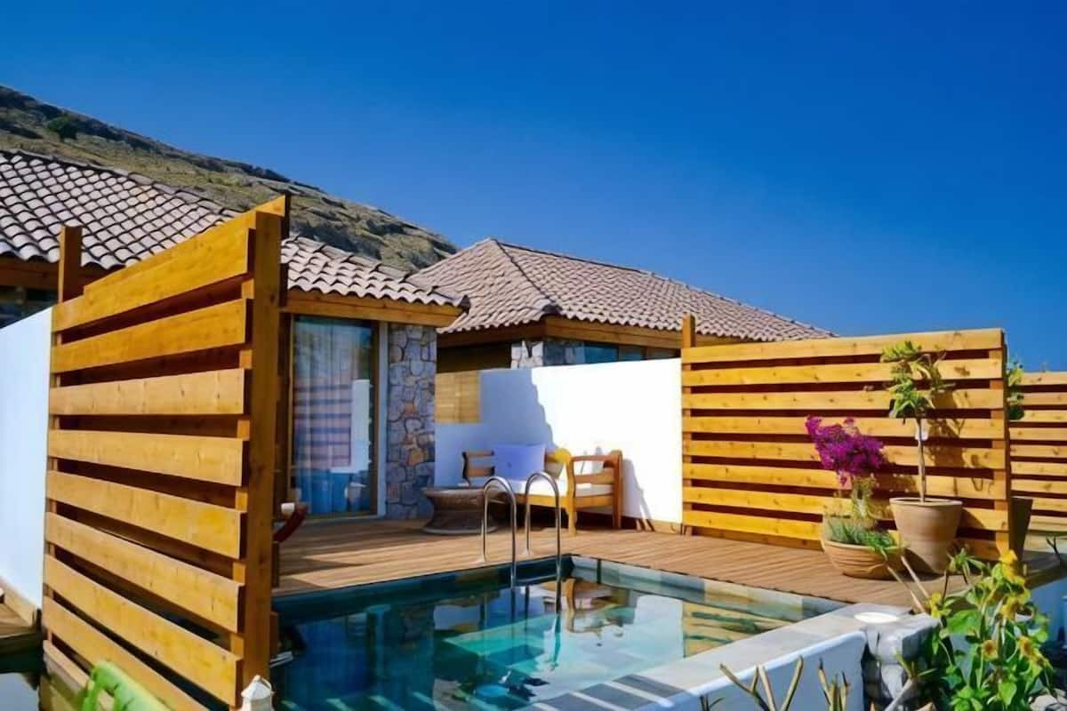 Ein Poolbereich mit Holzdeck, einem kleinen Schwimmbecken und einer Sitzgelegenheit mit Tisch und Stühlen.