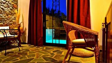 A wicker chair with a cushion, a table with a basket, and a stone-patterned floor.