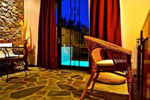 A wicker chair with a cushion, a table with a basket, and a stone-patterned floor. - Caesars Gardens Hotel & Spa - Adults Only (Rhodes)