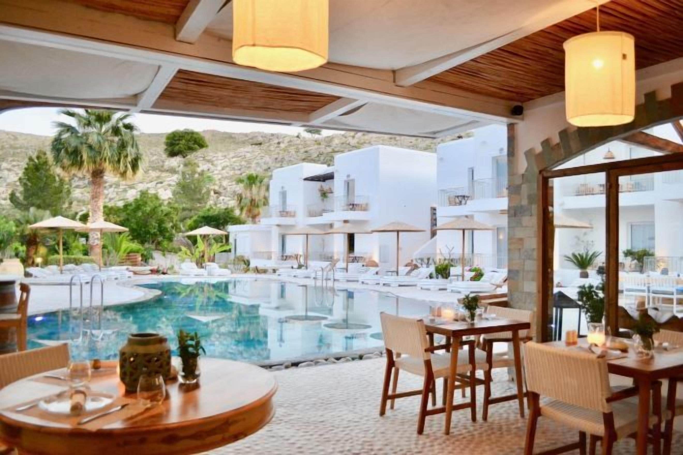 A poolside area with outdoor seating, a pool, and a view of a mountainous landscape.