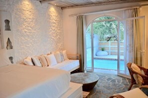 Une chambre avec un lit, un canapé, une table ronde et une vue sur une piscine, visible à travers une porte vitrée.