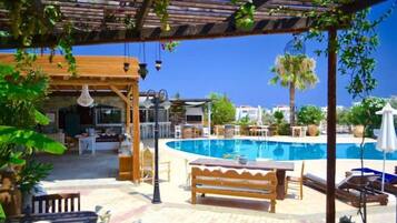 A poolside area with a wooden pergola, lounge chairs, and a pool.