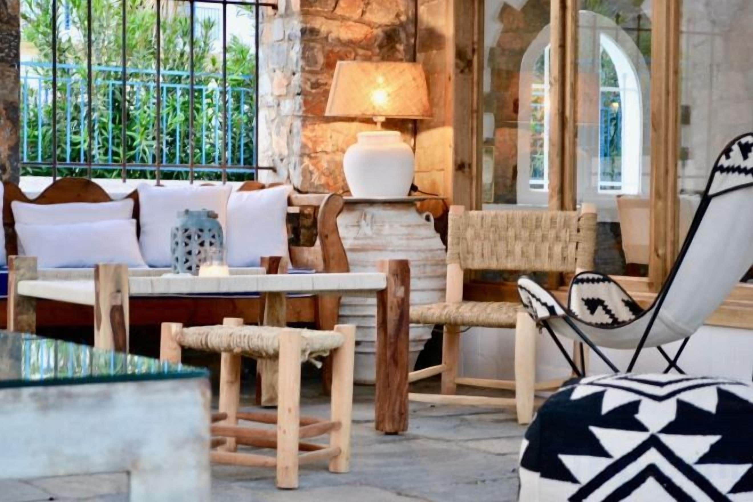 A cozy seating area with a sofa, chairs, and a table, a lamp, and a view through a window.
