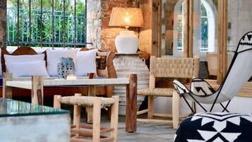 A cozy seating area with a sofa, chairs, and a table, a lamp, and a view through a window.
