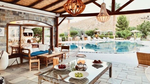 An outdoor seating area with a pool, stone walls, and wooden furniture.