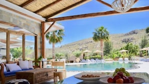 A poolside area with a wooden deck, lounge chairs, and a clear view of a mountainous landscape.