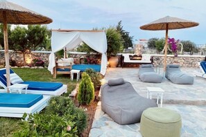An outdoor seating area with lounge chairs, a small table, and umbrellas. - Caesars Gardens Hotel & Spa - Adults Only (Rhodes)