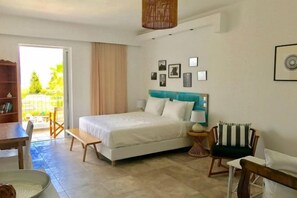 A bedroom with a bed, bedside table, chair, and a view of the outdoors. - Caesars Gardens Hotel & Spa - Adults Only (Rhodes)