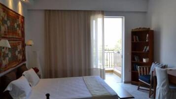 Una habitación de hotel con una cama, una estantería, una ventana con cortinas y vistas al exterior.