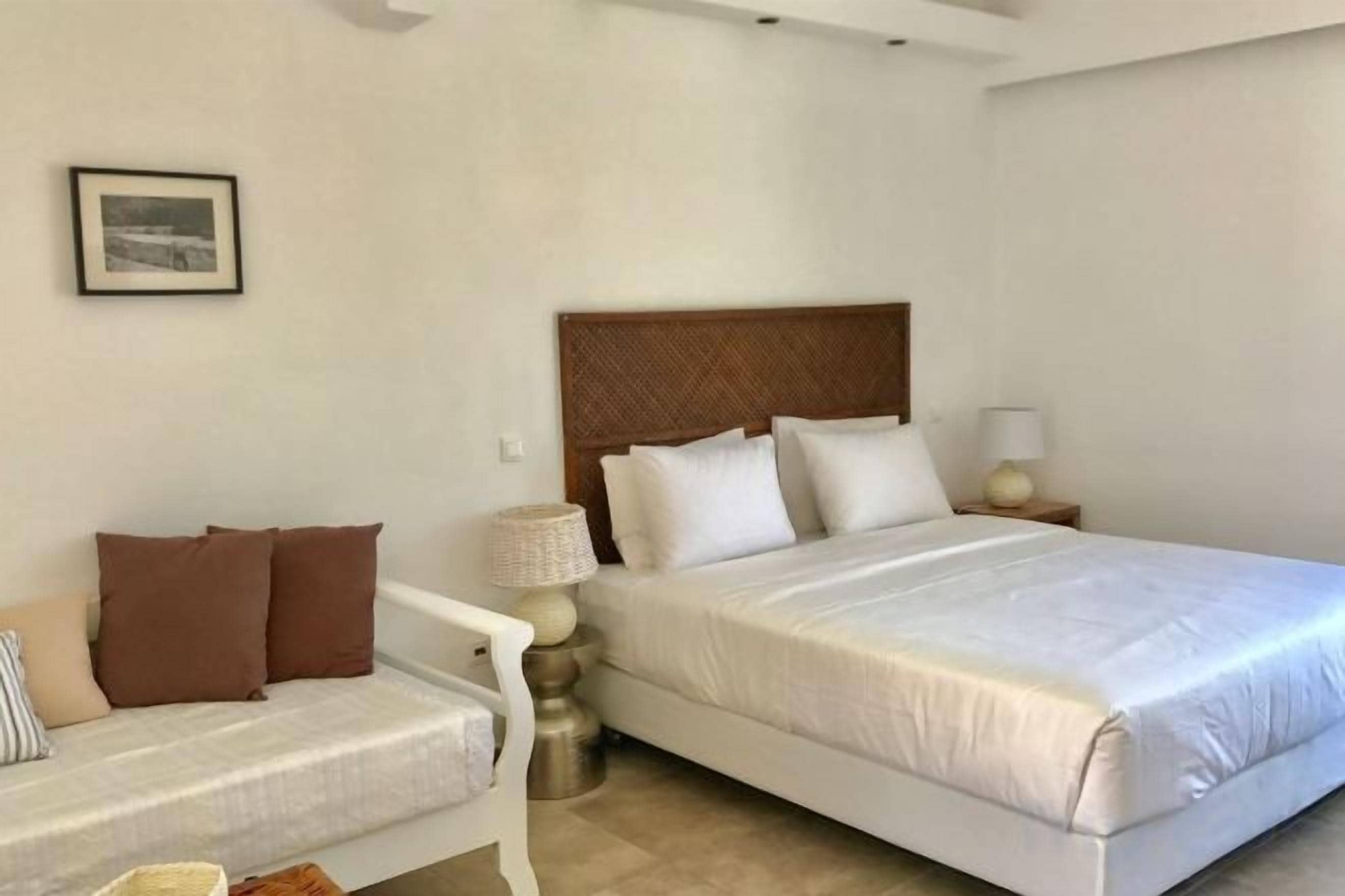 A hotel room with a bed, a bedside table with a lamp, and a sofa.