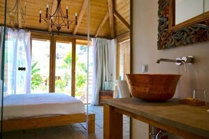 Una habitación con una cama, un gran comedor de madera, un lavabo rústico y vistas al exterior.