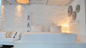 A white-themed bedroom with a bed, a wall-mounted lamp, and a textured wall.