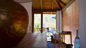A room with a wooden ceiling, a dining table, and a view of the outdoors.