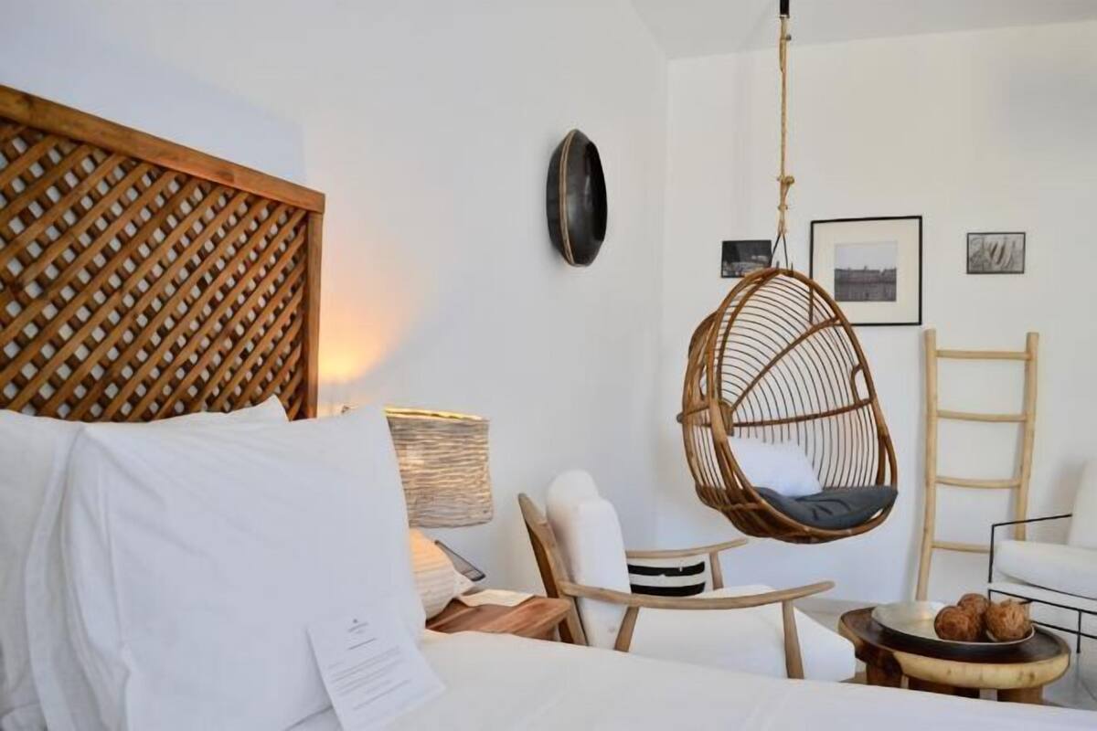 Ein Schlafzimmer mit einem Bett, einem Hängesessel, einem kleinen Tisch und einem Wandregal.