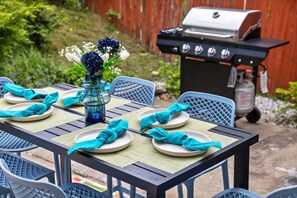 A table set outdoors with plates, napkins, and a vase of flowers.