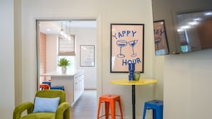 Une cuisine moderne avec une table jaune, des tabourets orange et bleus, et une chaise verte.