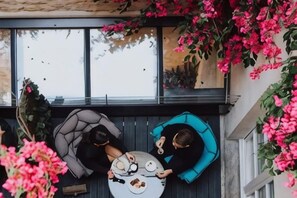 A rooftop terrace with two seating areas, one with a grey sofa and the other with a blue sofa, both facing a large window. - Hotel Dupond-Smith (Paris)