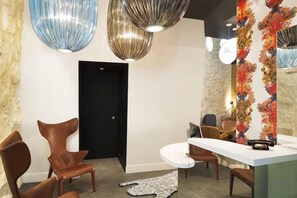 A modern interior with a stone wall, a black door, and a round dining table with chairs.