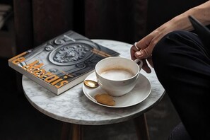 A book titled 'Le Koffer des' on a table with a cup of coffee and a spoon.
