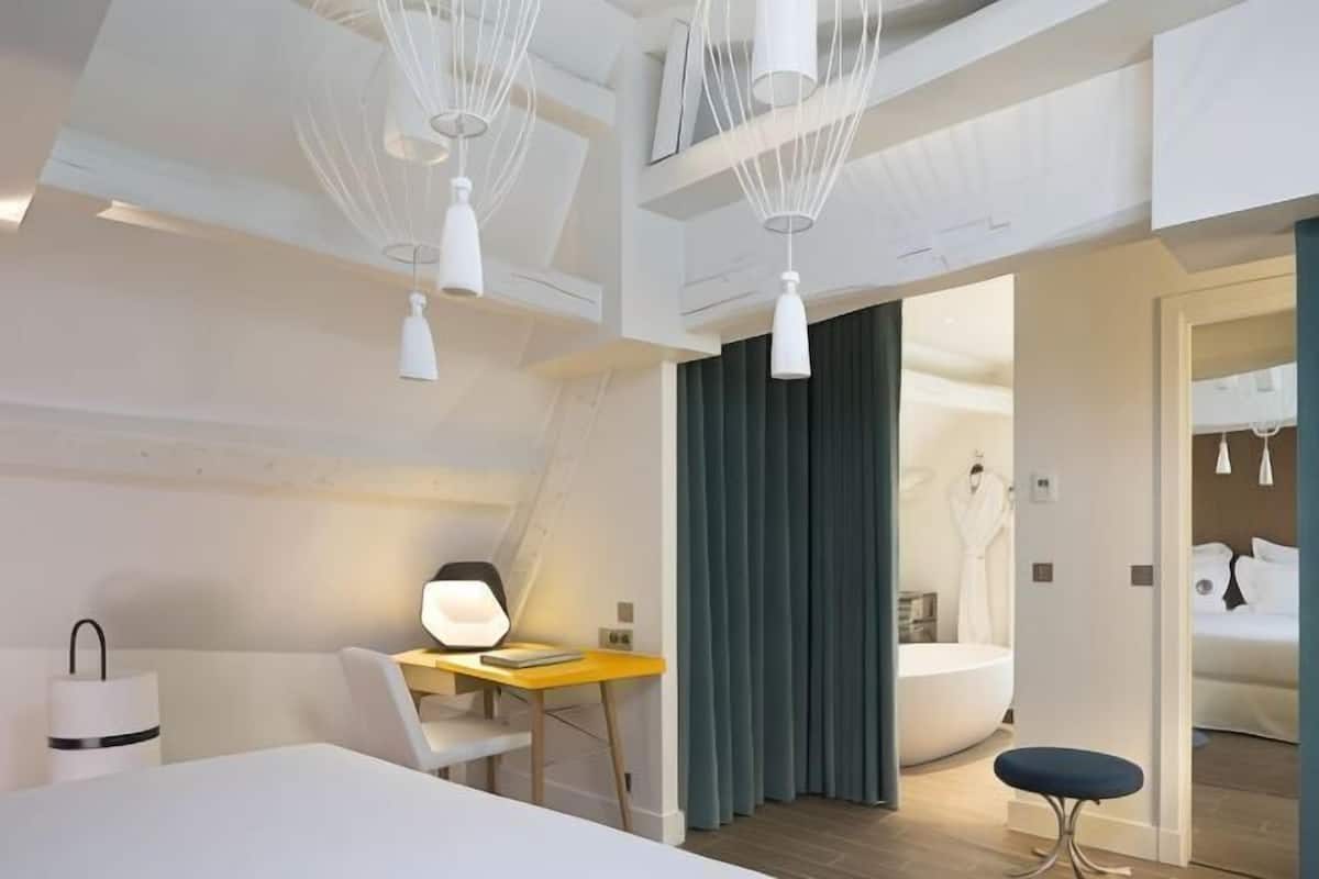 A modern hotel room with a desk, chair, and a large window.