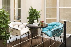 A balcony with two chairs, a table, and a potted plant. - Hotel Dupond-Smith (Paris)