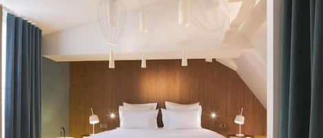 A modern hotel room with a large bed, pendant lighting, and a wooden accent wall.