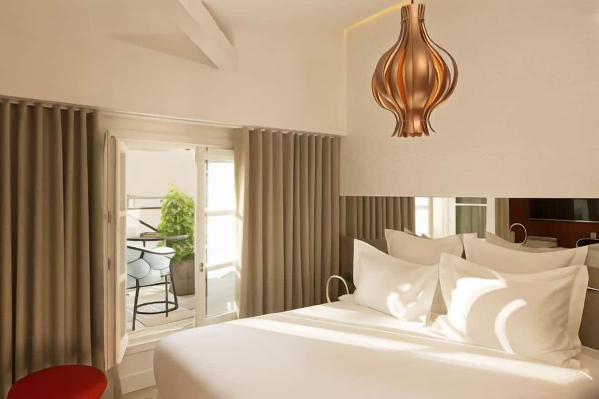A hotel room with a bed, curtains, a television, and a view of the outdoors.