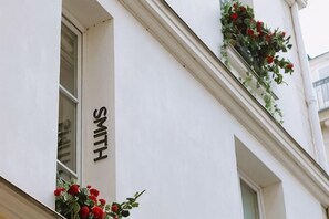 Un bâtiment avec une enseigne portant le nom « SMITH », une fenêtre ornée de fleurs rouges et une façade blanche.