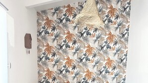 Una sala de estar con un sofá negro, un sillón amarillo y una mesa de centro redonda de madera con una planta.