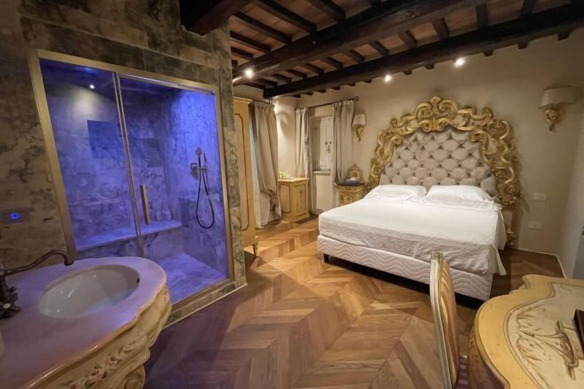 A bedroom with a large bed, a stone bathtub, and a wooden floor.
