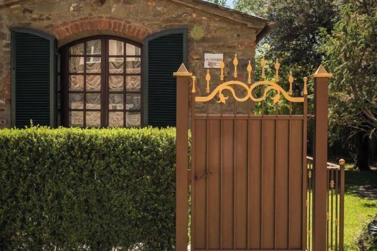 A stone building with a gated entrance, a sign above the gate, and a neatly trimmed hedge in front.