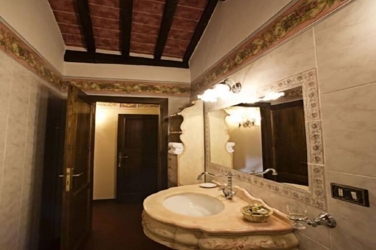 A bathroom with a marble sink, a large mirror, and a wooden door.