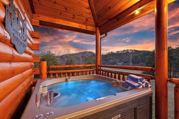 A wooden cabin with a hot tub, two glasses, and a sign on the wall.