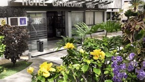 Entrada de un hotel con diseño moderno, destacando un frente de vidrio y un letrero que dice "HOTEL CATALONIA ORO NESTO".