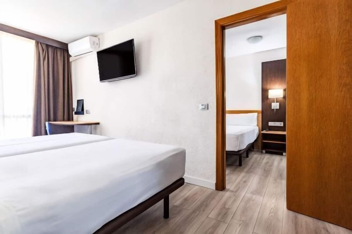 Ein Hotelzimmer mit einem Bett, einem Schreibtisch, einem Fernseher und einem durch eine offene Tür einsehbaren Badezimmer.