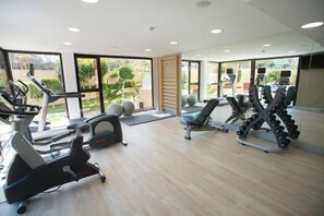 Un gimnasio con cintas de correr, elípticas y equipo de pesas.