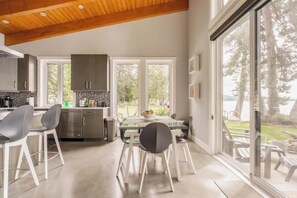 A modern kitchen with a dining area, large windows, and a view of the outdoors. - Secluded, peaceful, ocean front home. Close to all amenities/outdoor activities. (Sooke)