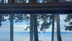 Une pièce dotée d’une grande porte-fenêtre coulissante donnant sur un paysage magnifique, avec un lac et des montagnes en toile de fond.